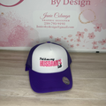 Purple and white cap with text on a wooden surface and floral background