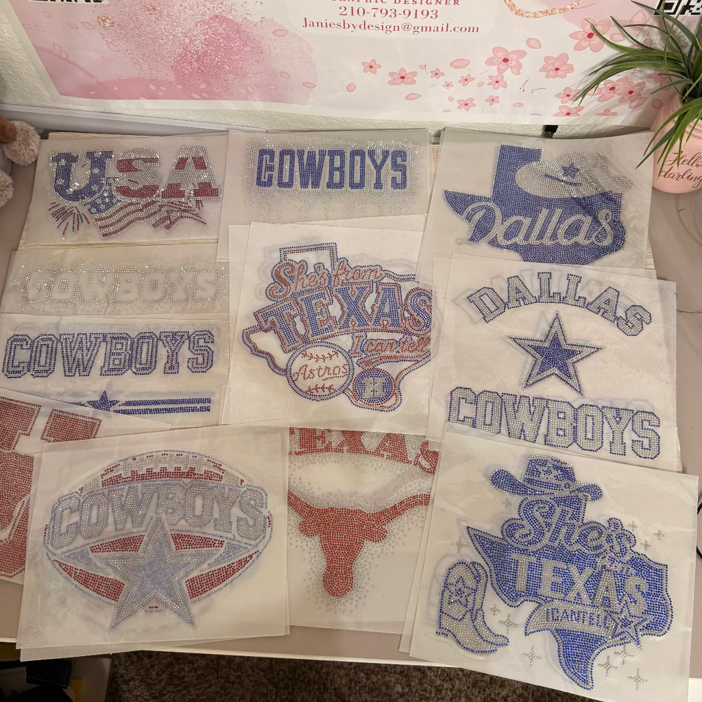 A grid of embroidered or printed Texas Cowboys-themed designs on white fabric squares, displayed beneath a pink branded sign that reads Jane's By Design. The designs include blue and red text and logos such as 'Cowboys,' 'Dallas,' 'She's Texas,' and 'USA.