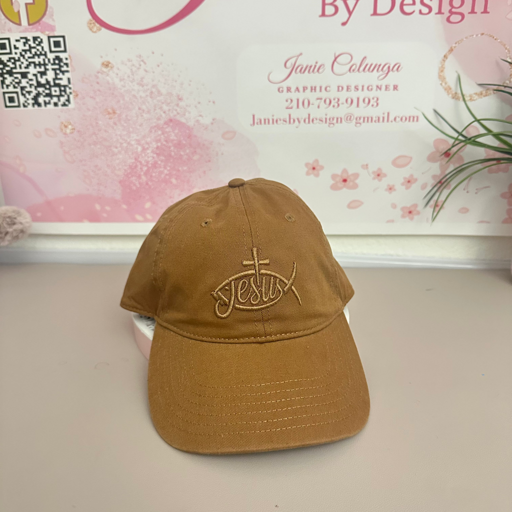 Brown cap with 'Jesus' embroidery on a white surface with a branded background.