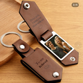 Brown leather keychain with photo insert and engraved text on a wooden surface