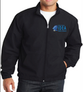 A man wearing a black Port Authority essential jacket with an embroidered logo on the left chest area. The jacket has a zipper and appears to be made of polyester.