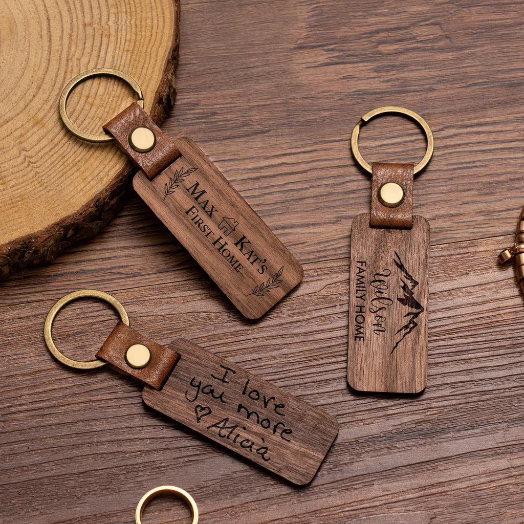 Three wooden keychains with engraved text on a wooden surface