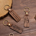 Three wooden keychains with engraved text on a wooden surface