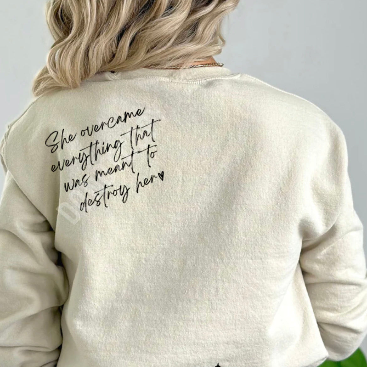 A woman wearing a beige long-sleeved t-shirt with text printed on the front.